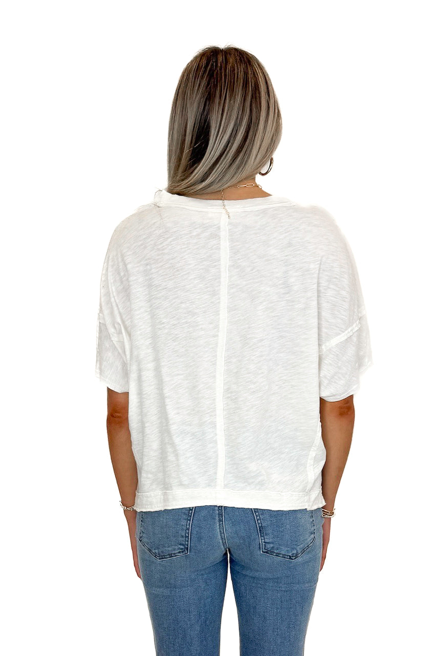 Back view of woman wearing Cream V-Neck Tee with jeans against white studio background