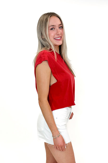 SIde view of woman wearing Red Boxy Tee with jean shorts against white studio background.