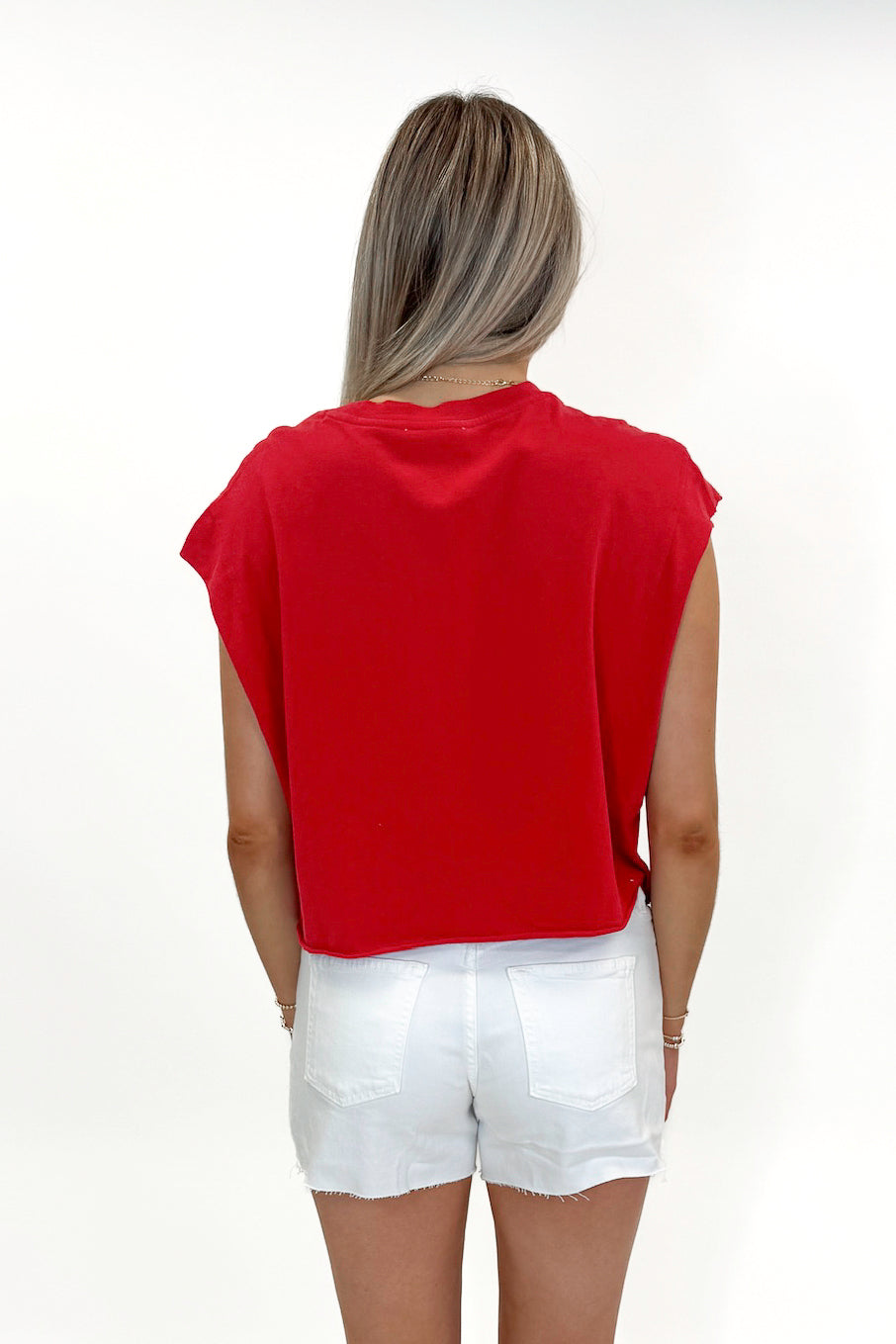 Back view of woman wearing Red Boxy Tee with jean shorts against white studio background.