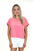 Front view of woman wearing Pink Cut Out Back Tee with jean shorts against white studio background.