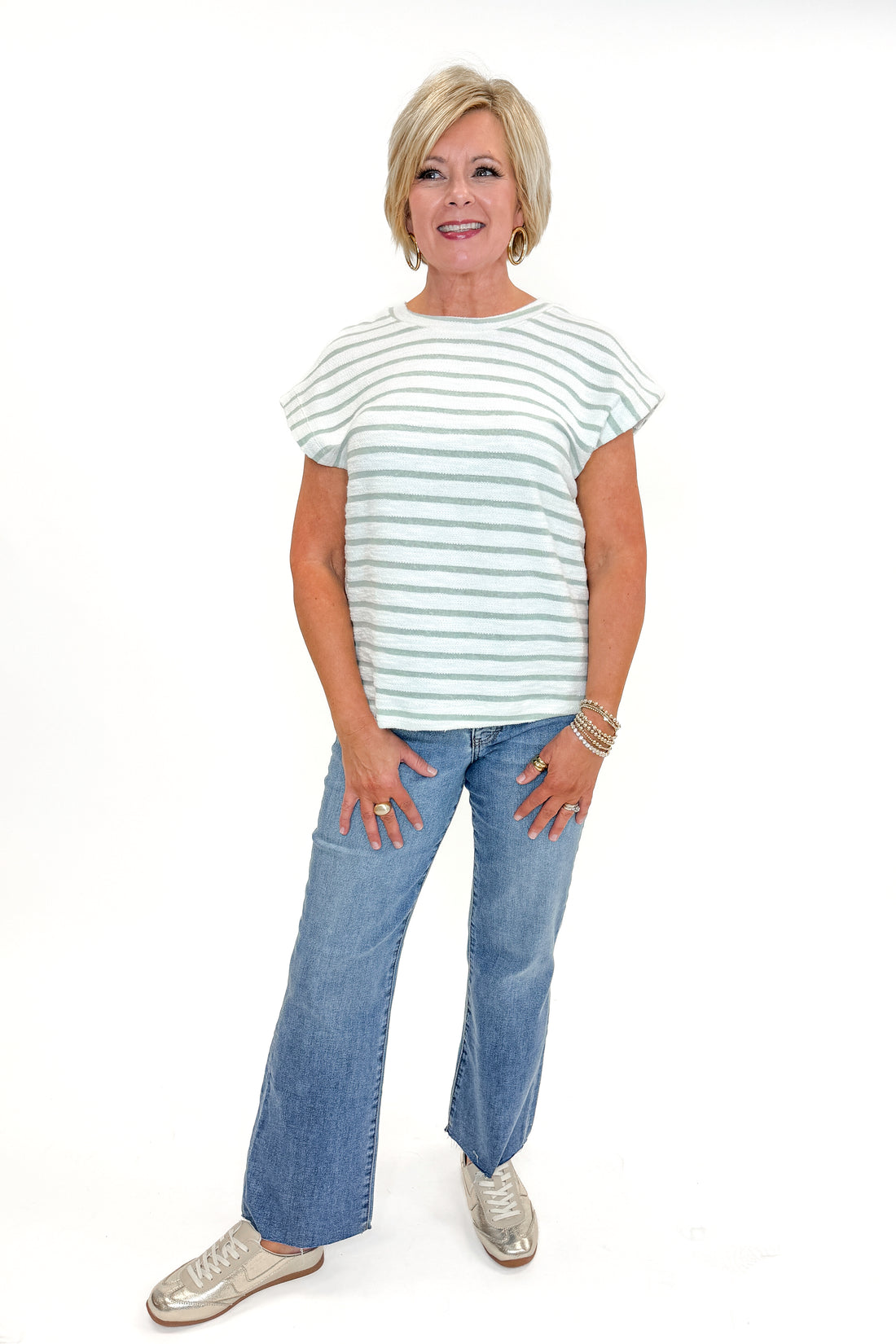 Front view of woman wearing Sage &amp; White Striped Terry Top with jeans against white studio background.