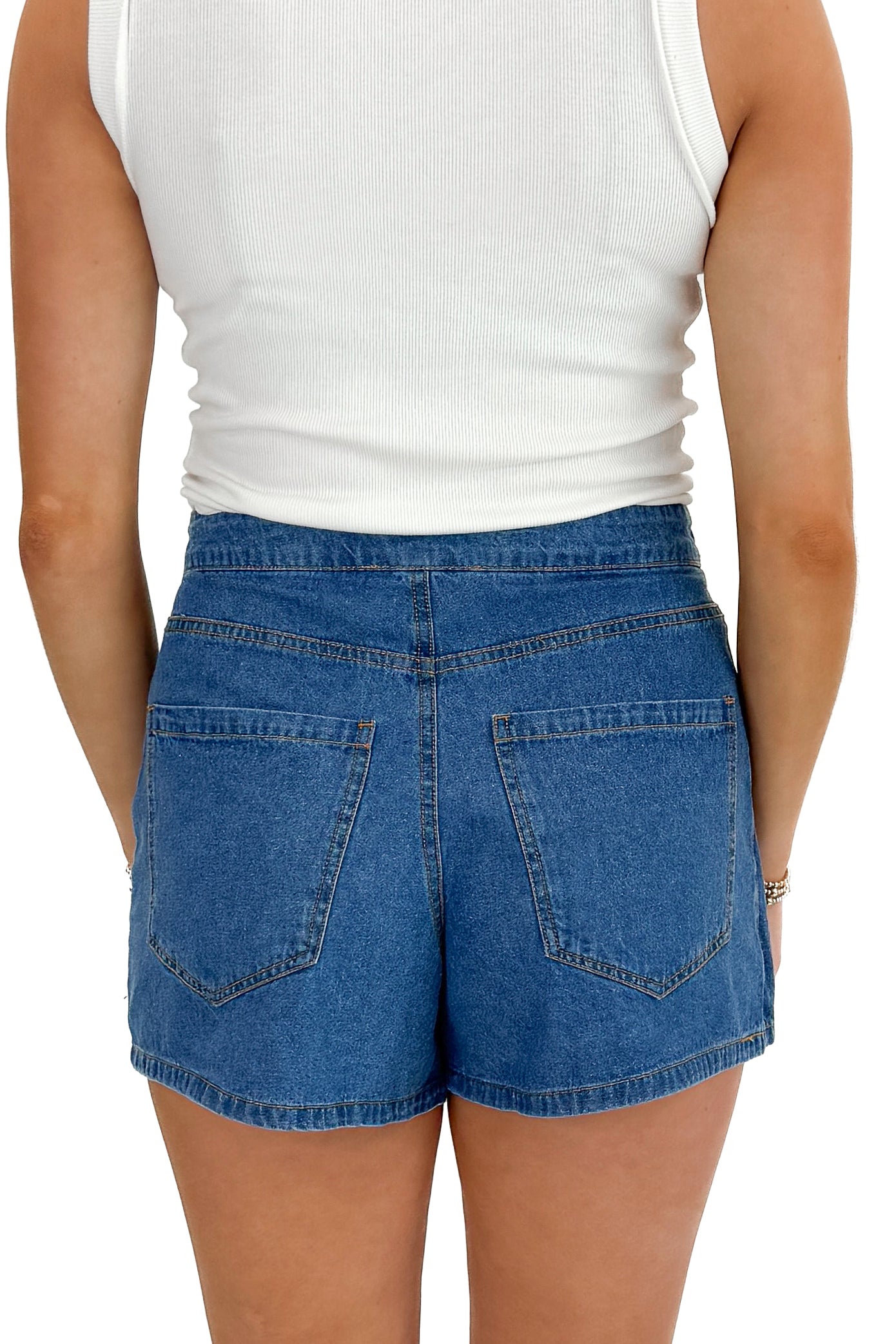 Back view of woman wearing white top with Medium Wash Denim Wrap Skort against white studio background.
