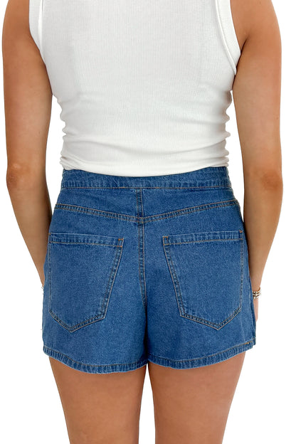 Back view of woman wearing white top with Medium Wash Denim Wrap Skort against white studio background.