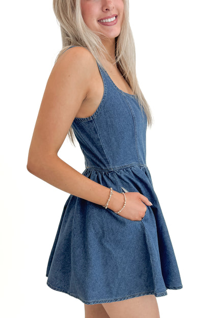 Side view of woman wearing Denim Tank Dress against white studio background.