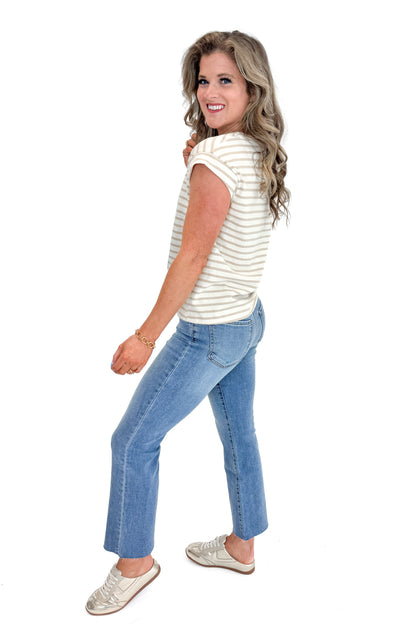 Side view of woman wearing Taupe &amp; Cream Stripe Cap Sleeve Tee with jeans against white studio background.