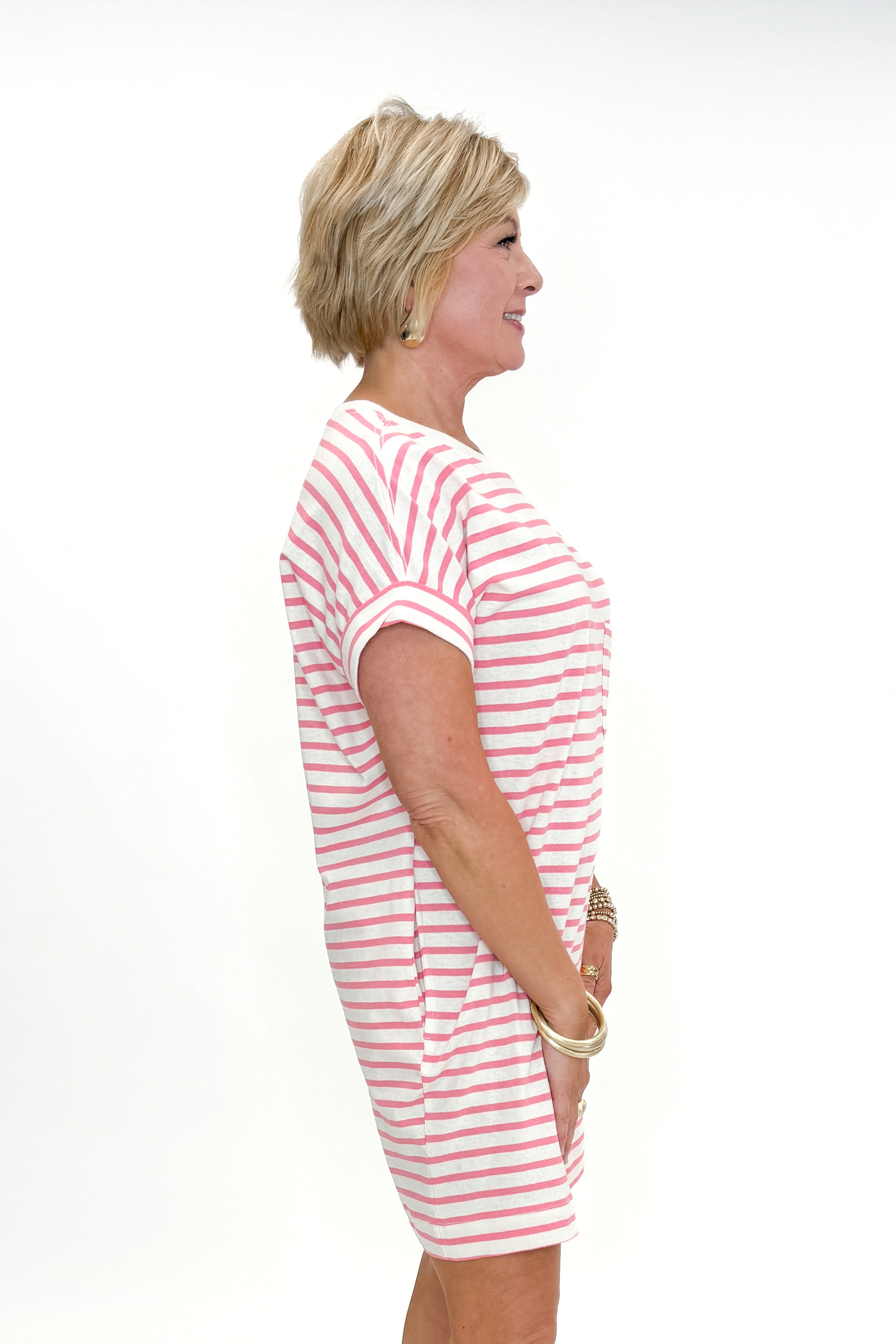 Side view of woman wearing Pink &amp; Cream Striped Short Sleeve Dress against white studio background.