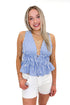 Front view of woman wearing Blue Striped Smocked Peplum Tank with jean shorts against white studio background.