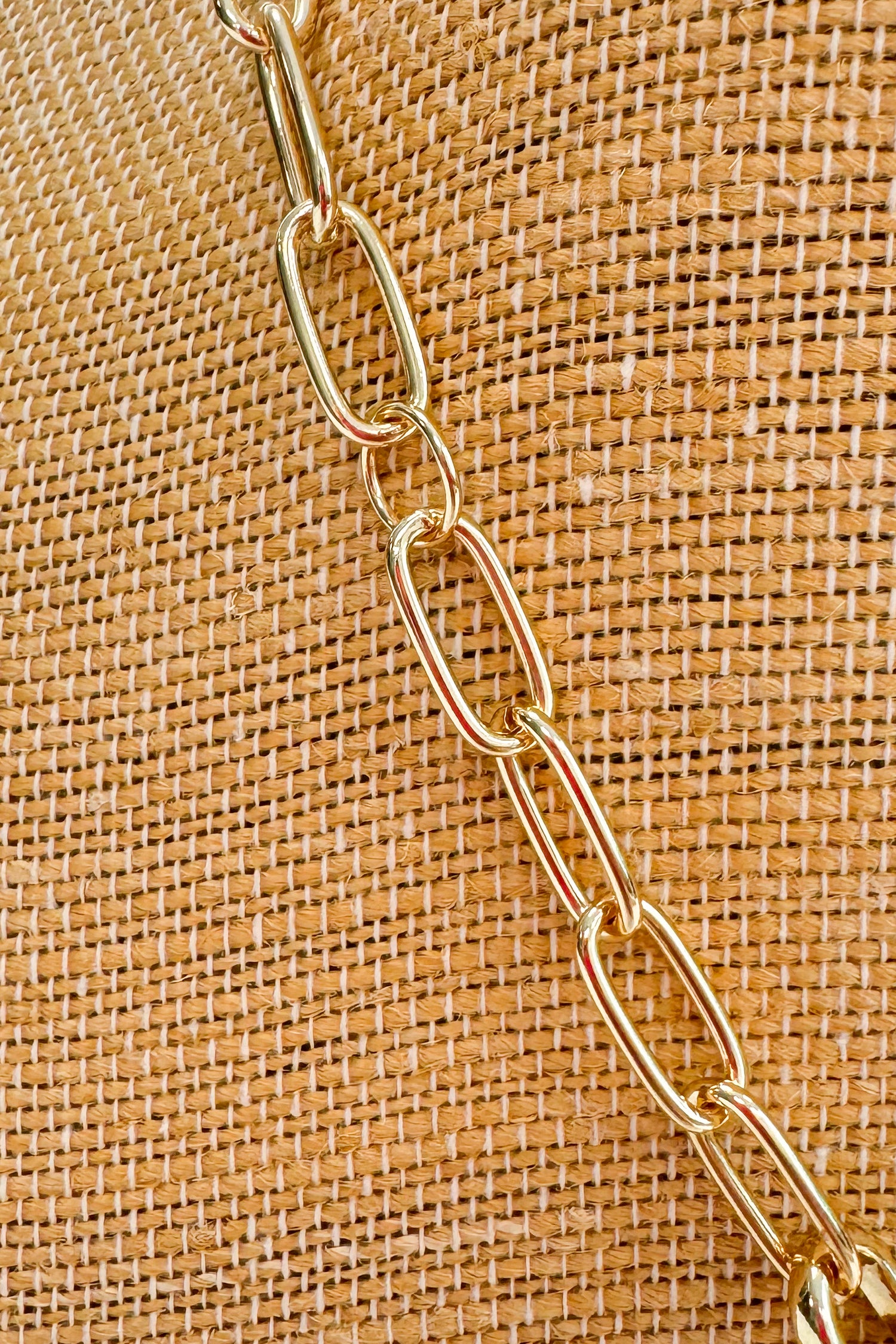 Gold chain on a textured brown fabric background