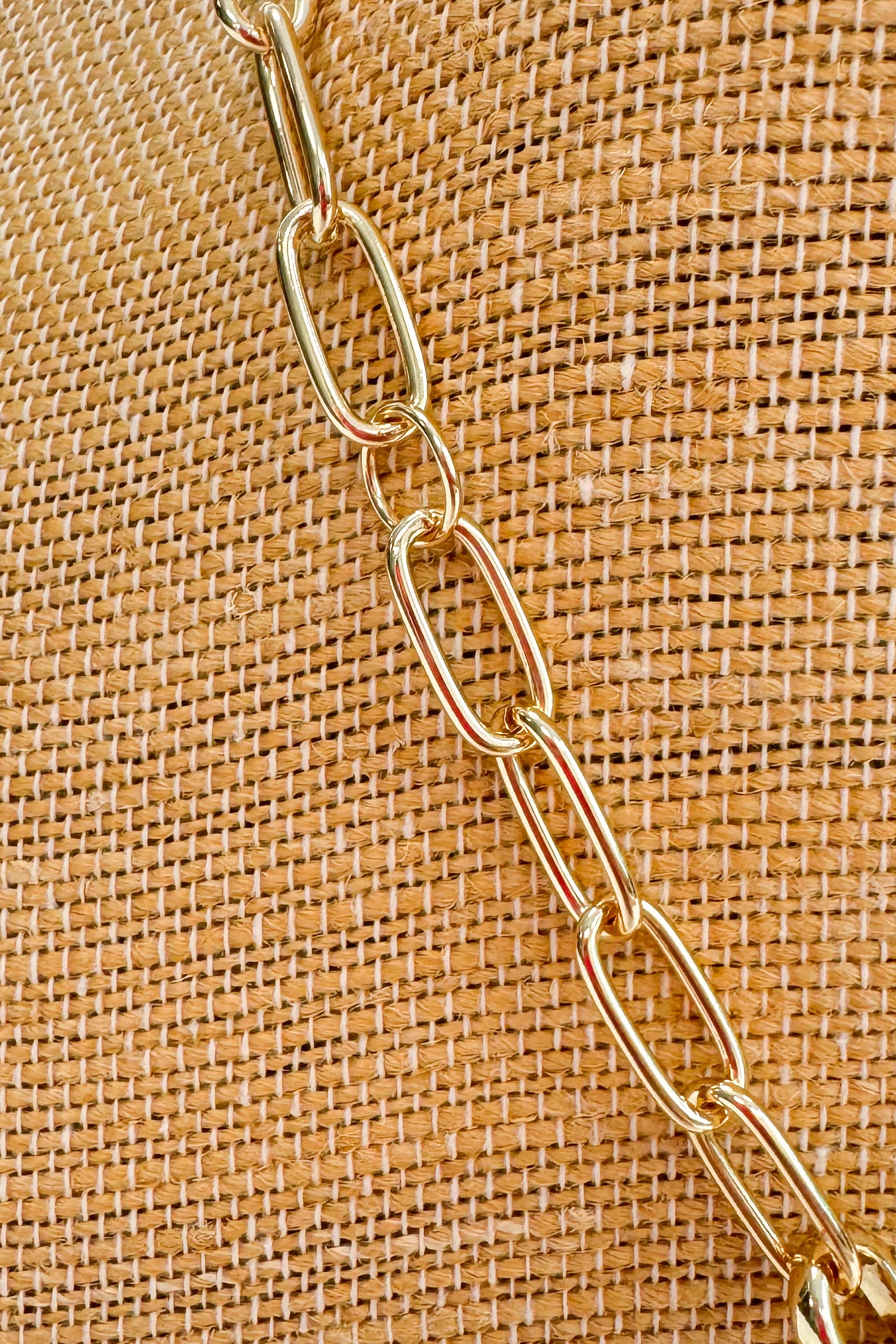 Gold chain on a textured brown fabric background
