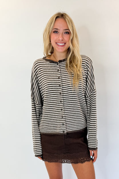 Front view of woman wearing Swagger Boutique’s Dark Brown &amp; Cream Striped Button Up Cardigan with skirt against white studio background.