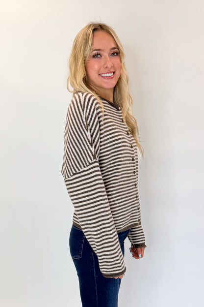 Side view of woman wearing Swagger Boutique’s Dark Brown &amp; Cream Striped Button Up Cardigan with skirt against white studio background.
