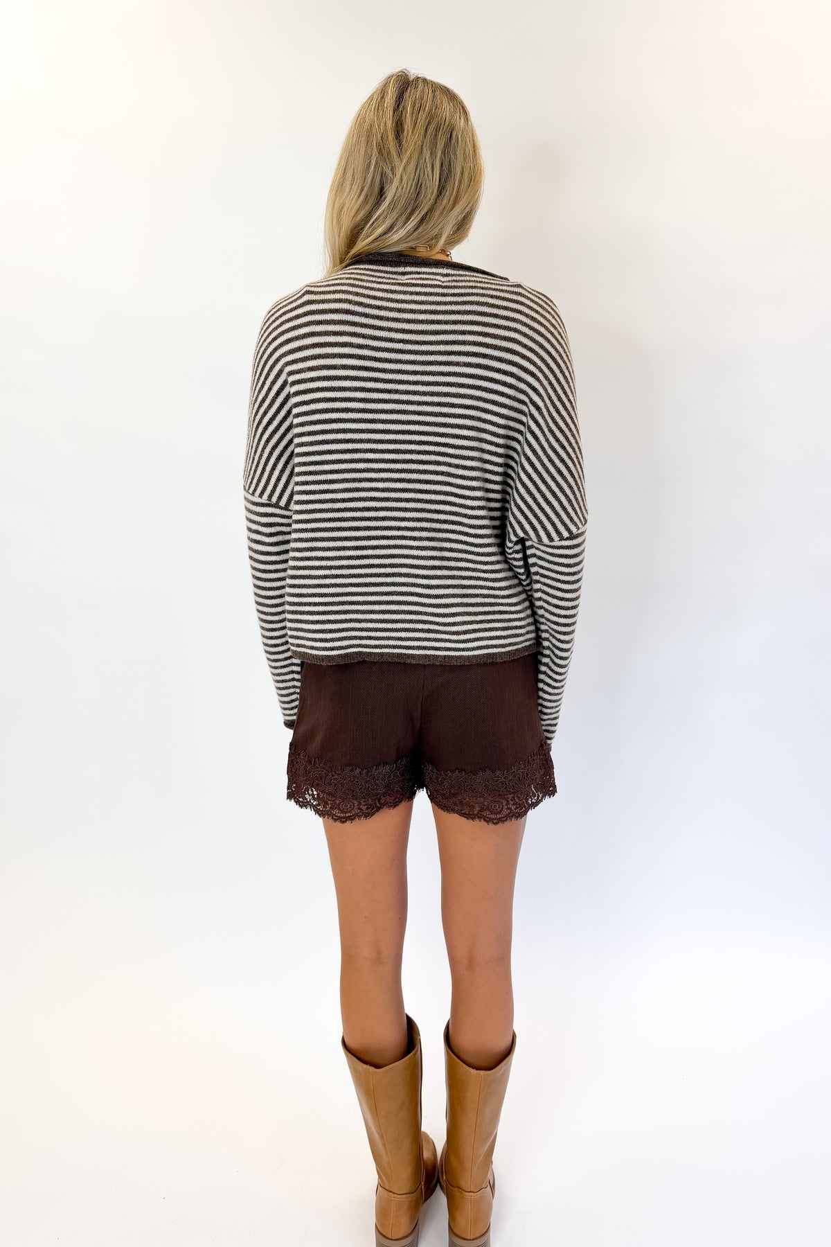 Back view of woman wearing Swagger Boutique’s Dark Brown &amp; Cream Striped Button Up Cardigan with skirt against white studio background.