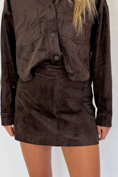 Front detail view of woman wearing Swagger Boutique’s All Day Cropped Suede Jacket and Perri Suede Mini Skirt by Z Supply In Dark Chocolate against white studio background.