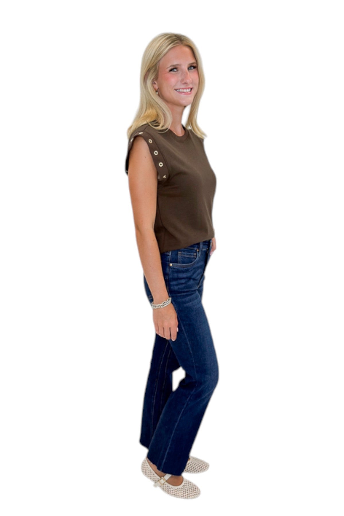 Side view of woman wearing Swagger Boutique’s Dark Chocolate Camino Grommet Top by Z Supply with jeans against white studio background.