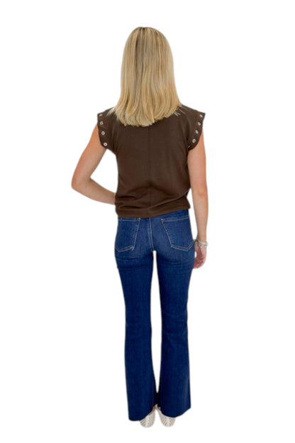 Back view of woman wearing Swagger Boutique’s Dark Chocolate Camino Grommet Top by Z Supply with jeans against white studio background.