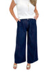 Front detail view of woman wearing Swagger Boutique’s Dark Wash Pleated Trouser Jeans by Risen with sweater against white studio background.