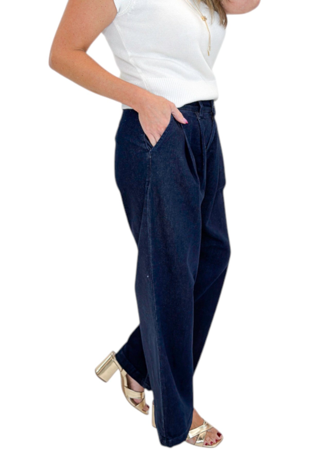 Side detail view of woman wearing Swagger Boutique’s Dark Wash Pleated Trouser Jeans by Risen with sweater against white studio background.