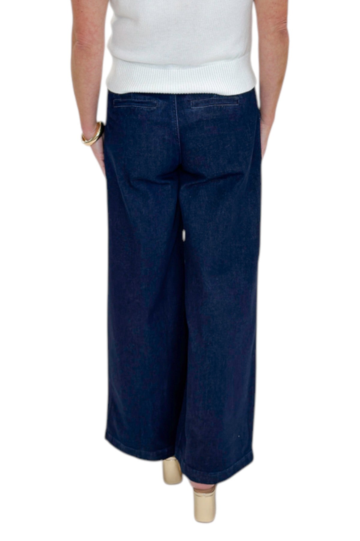 Back view of woman wearing Swagger Boutique’s Dark Wash Pleated Trouser Jeans by Risen with sweater against white studio background.