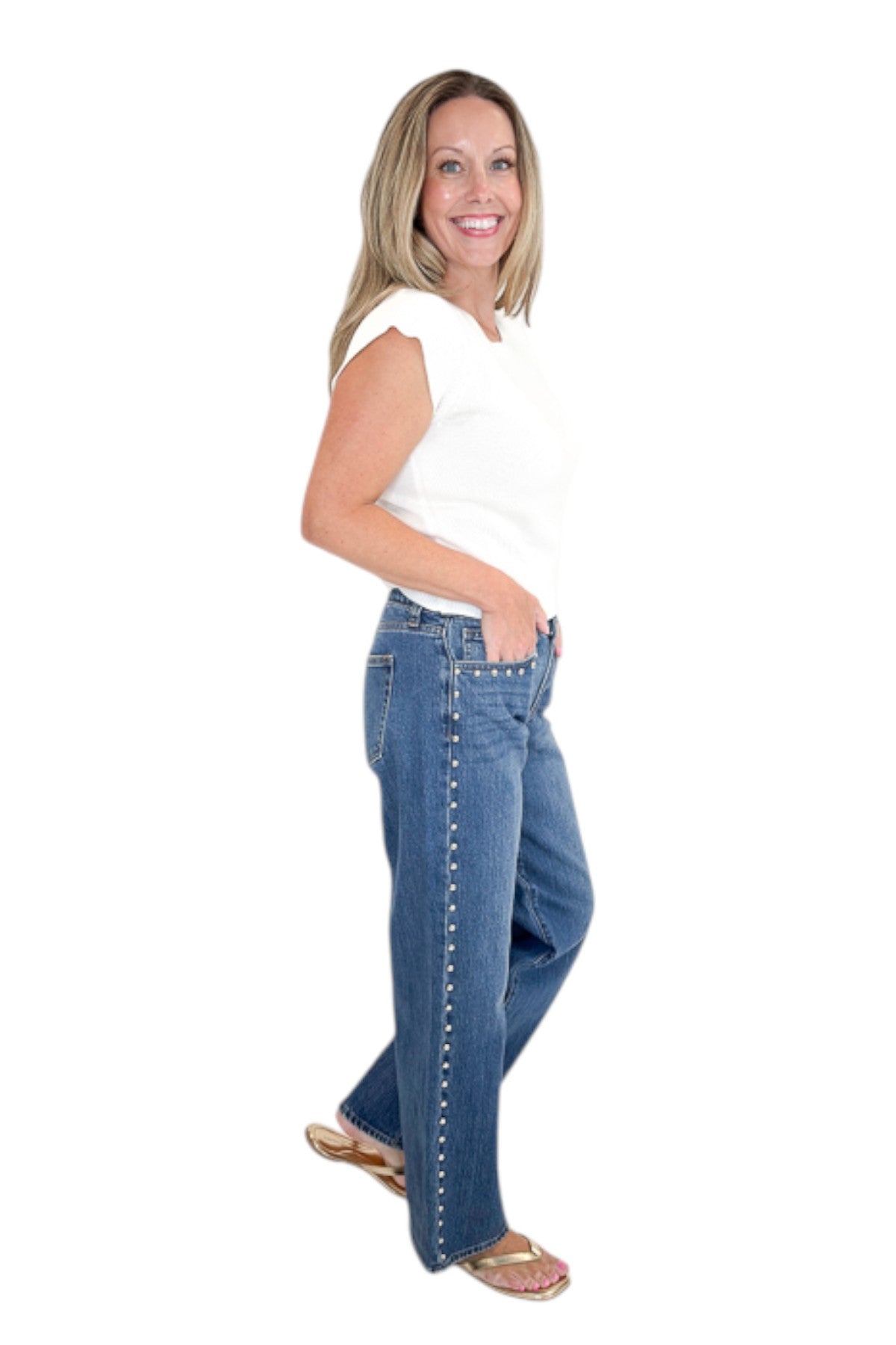 Side view of woman wearing Swagger Boutique’s sweater with Dark Wash Stud Jeans by Just Black Denim against white studio background.
