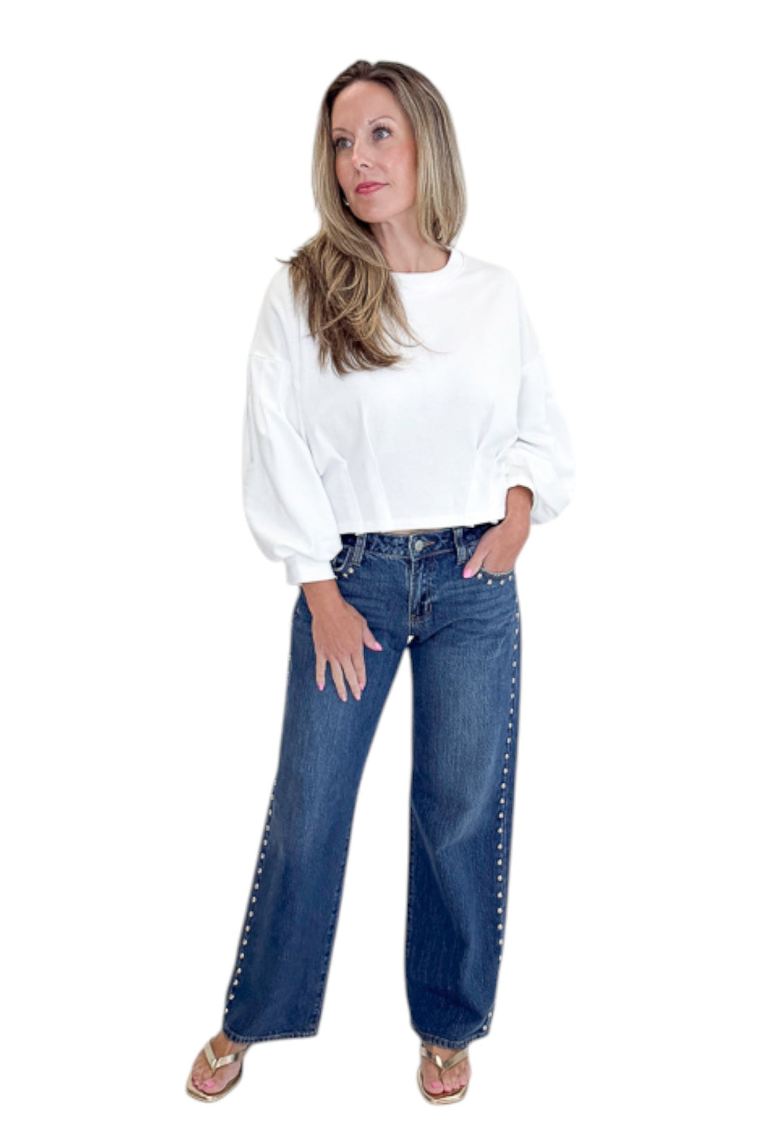 Front view of woman wearing Swagger Boutique’s sweater with Dark Wash Stud Jeans by Just Black Denim against white studio background.