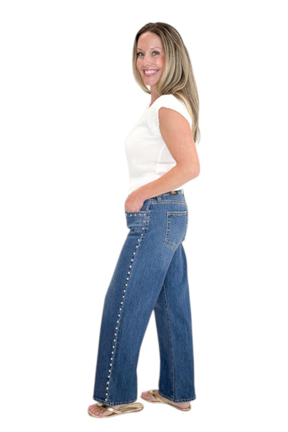 Side view of woman wearing Swagger Boutique’s sweater with Dark Wash Stud Jeans by Just Black Denim against white studio background.
