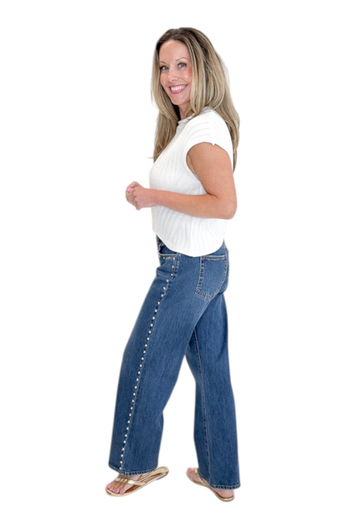 Side view of woman wearing Swagger Boutique’s sweater with Dark Wash Stud Jeans by Just Black Denim against white studio background.