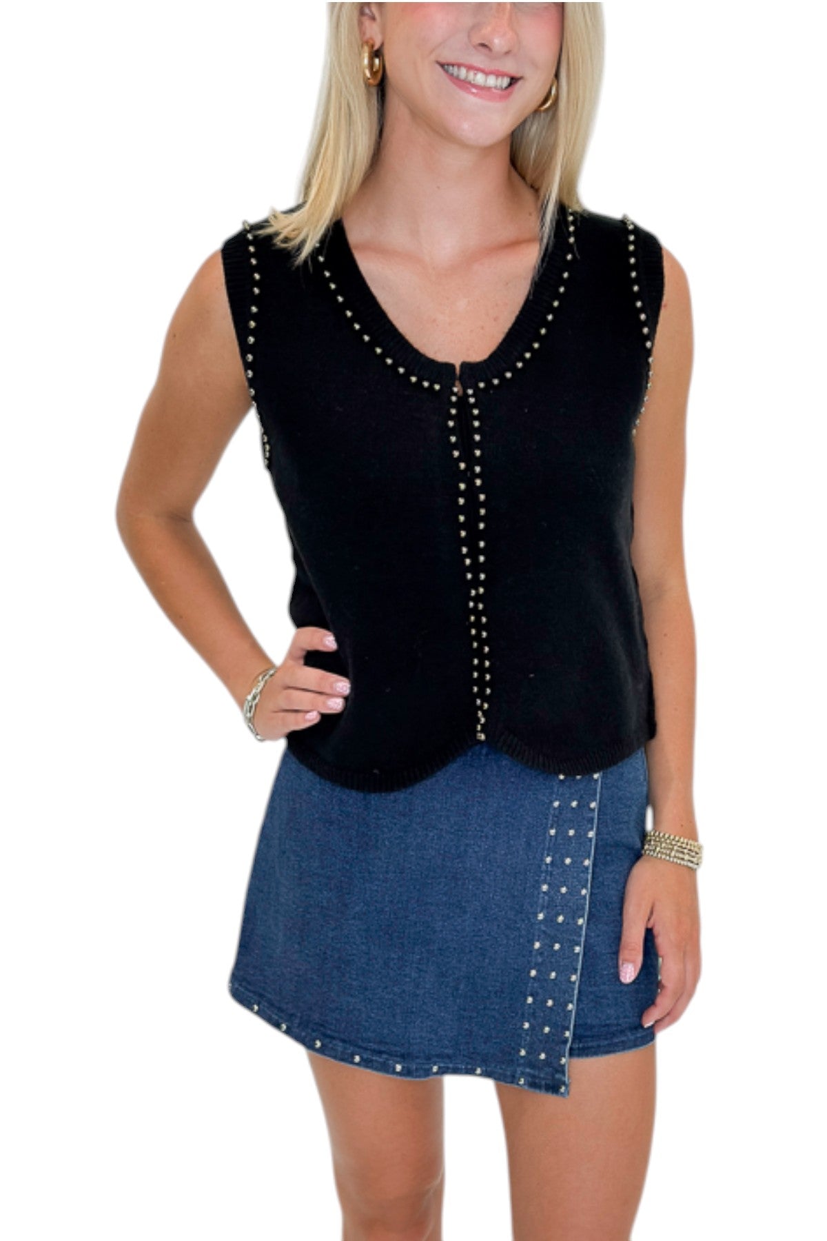 Front view of woman wearing Swagger Boutique’s Black Studded Sweater Vest with Dark Wash Studded Denim Skort against white studio background.
