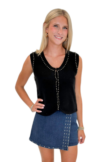 Front view of woman wearing Swagger Boutique’s Black Studded Sweater Vest with Dark Wash Studded Denim Skort against white studio background.