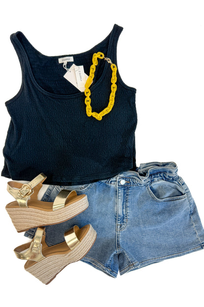 Flat lay of Denim Elastic Waist Shorts by Just Black Denim with black tank against white studio background. 