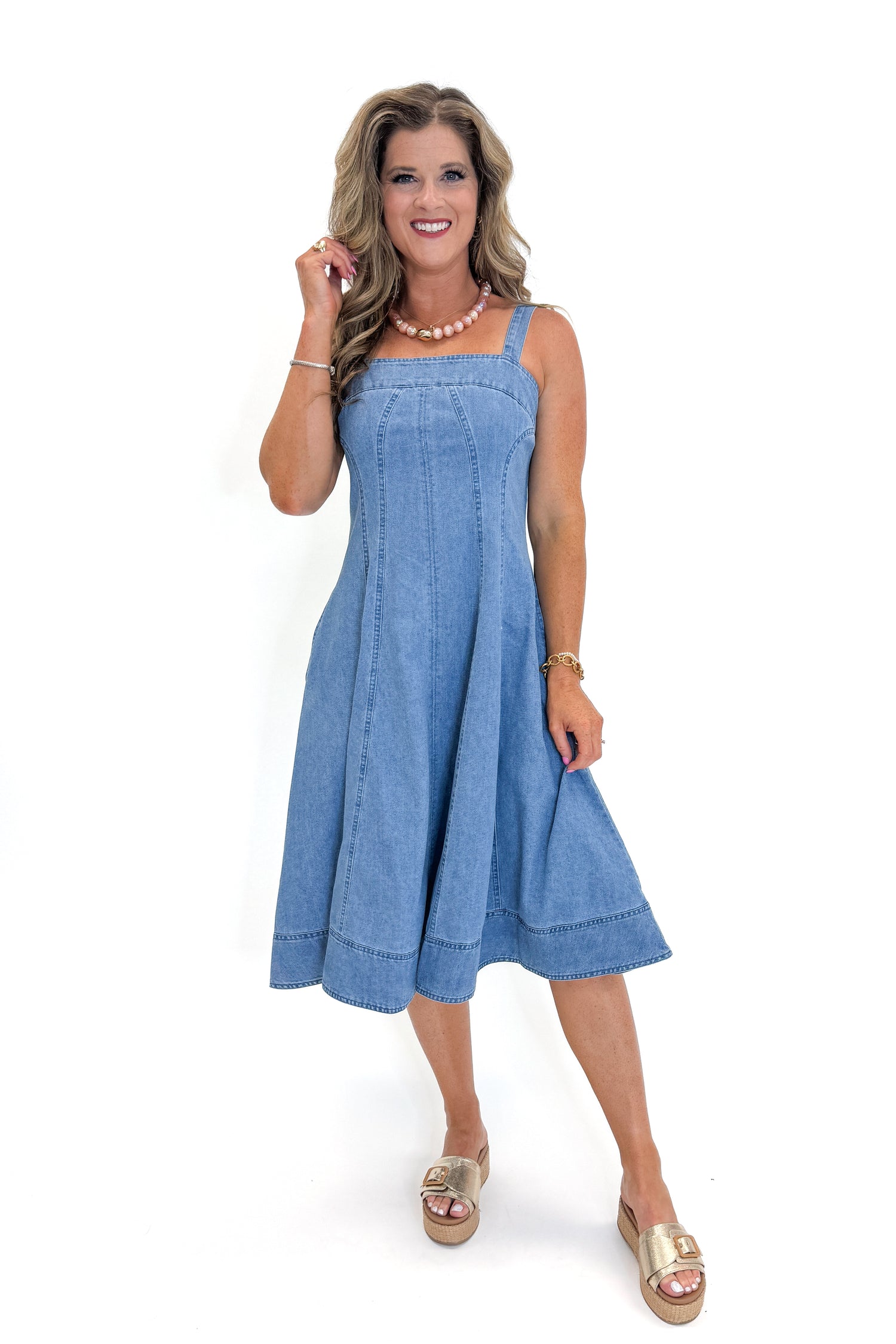 Front view of woman wearing Swagger Boutique’s Denim Fit &amp; Flare Midi Dress with jeans sandals white studio background.