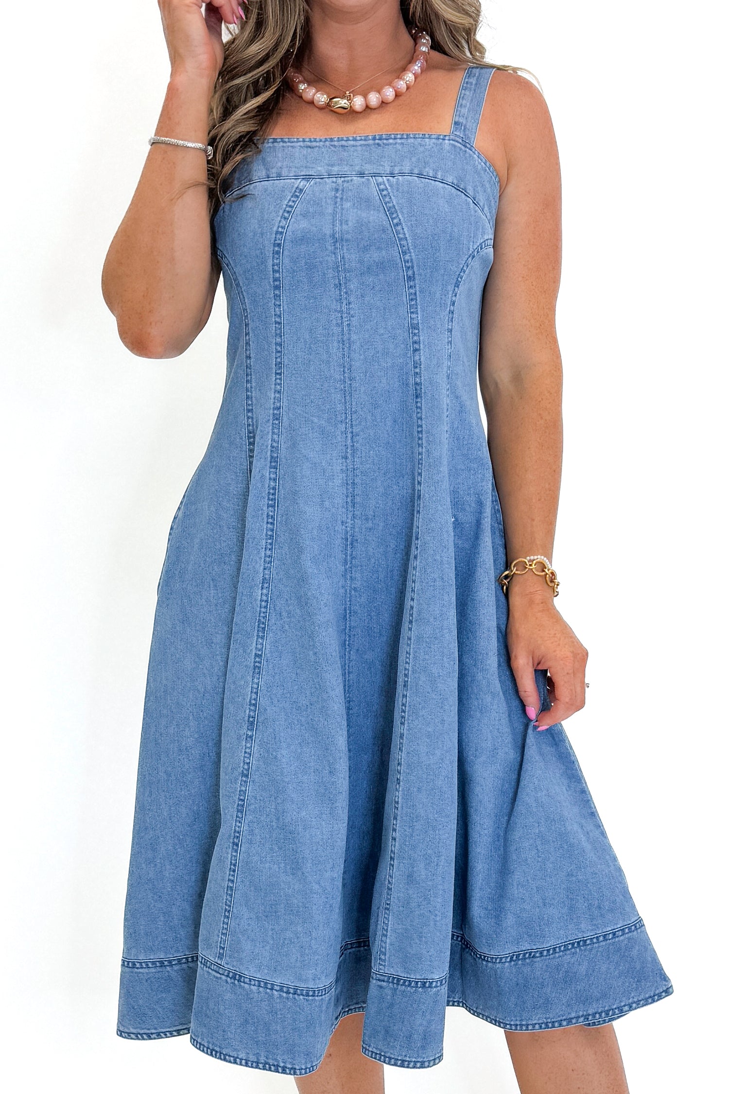 Front detail view of woman wearing Swagger Boutique’s Denim Fit &amp; Flare Midi Dress with jeans sandals white studio background.