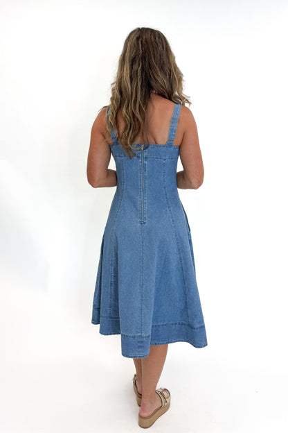 Back view of woman wearing Swagger Boutique’s Denim Fit &amp; Flare Midi Dress with jeans sandals white studio background.