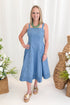 Front view of woman wearing Swagger Boutique’s Denim Fit & Flare Midi Dress with jeans sandals with a decorative background.