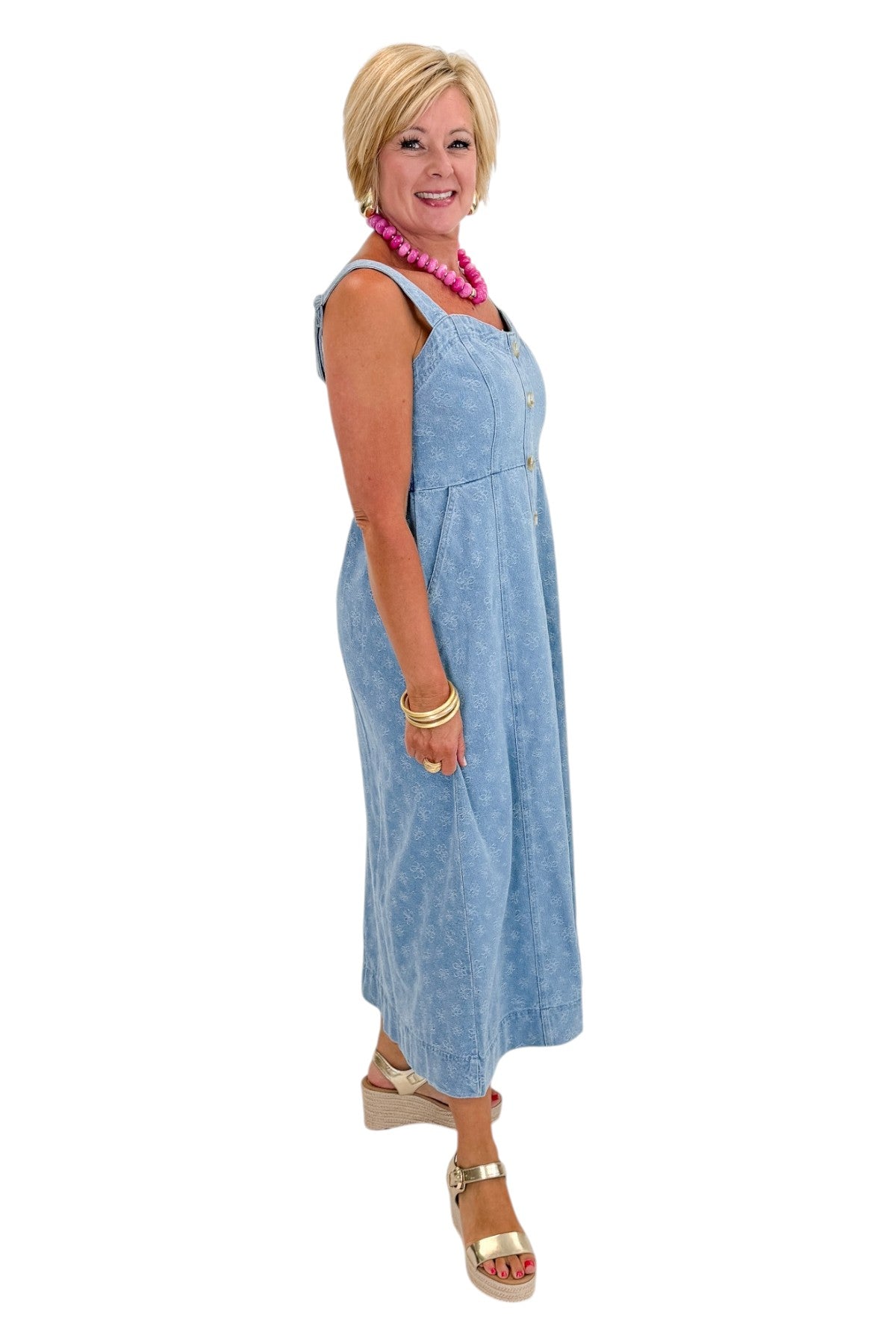 Side view of woman wearing Swagger Boutique’s Denim Floral Textured Midi Dress with wedges against white studio background.