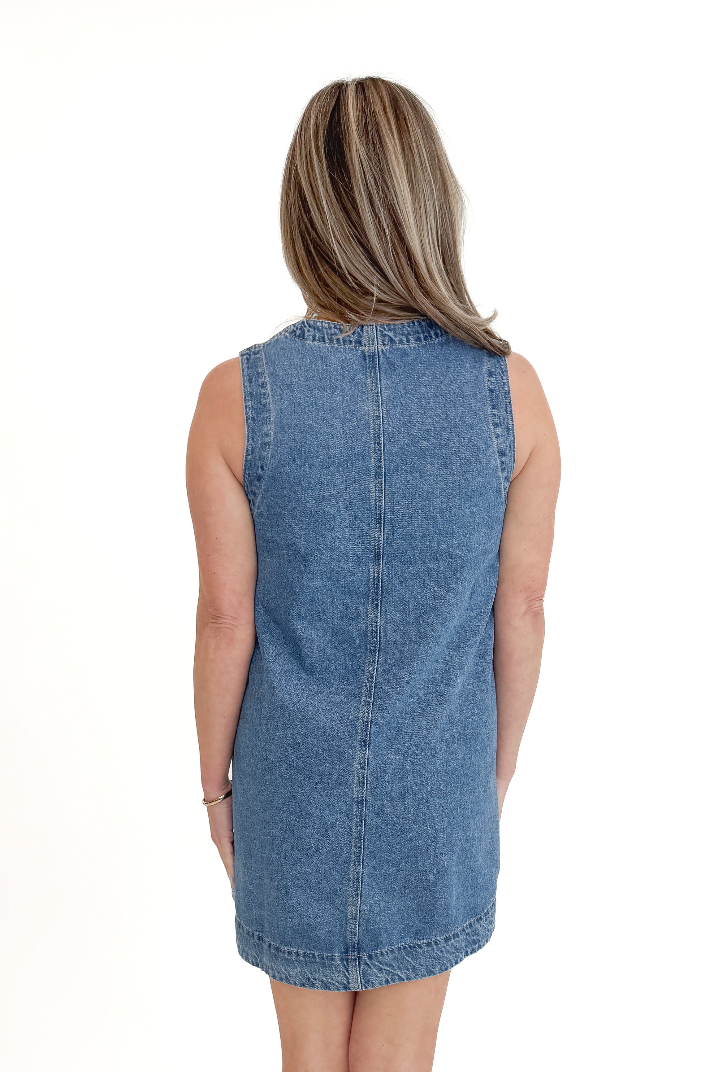 Back view of woman wearing Denim Pocket Detail Dress with sandals against white studio background.v