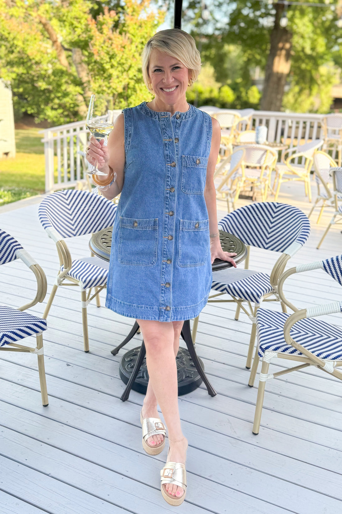 Front view of woman wearing Denim Pocket Detail Dress with sandals outside at a restaurant.