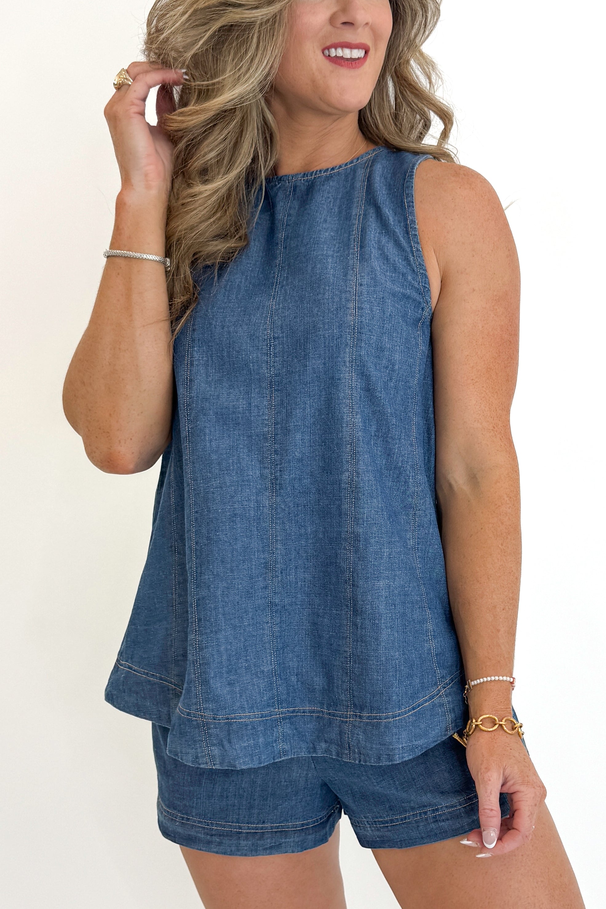 Front detail view of woman wearing Swagger Boutique’s Denim Seam Detail Swing Tank with matching Denim Seam Detail Shorts against white studio background.