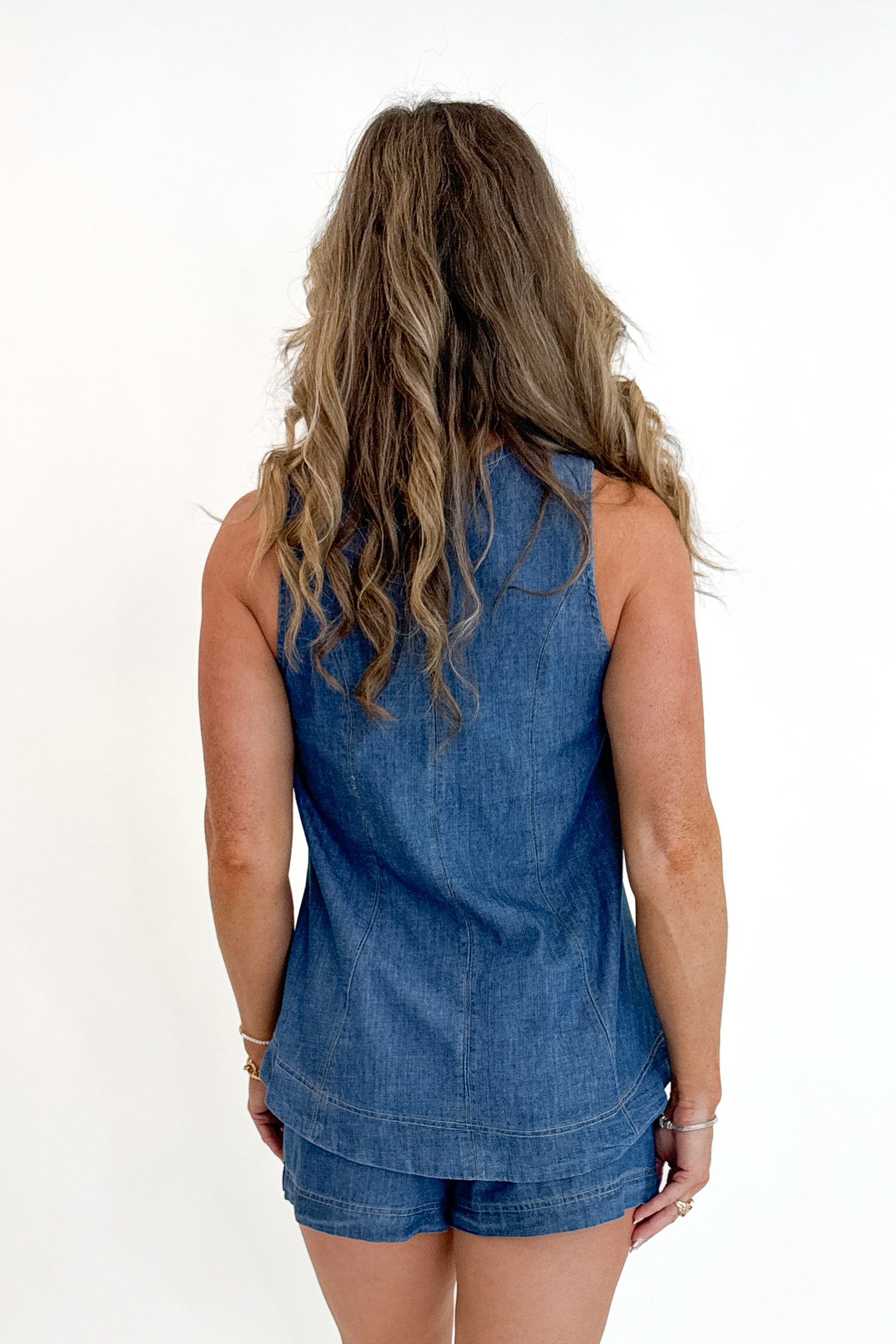 Back view of woman wearing Swagger Boutique’s Denim Seam Detail Swing Tank with matching Denim Seam Detail Shorts against white studio background.