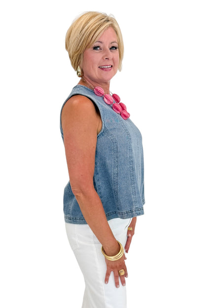 Side view of woman wearing Swagger Boutique’s Denim Seamed Sleeveless Top with jeans against white studio background.