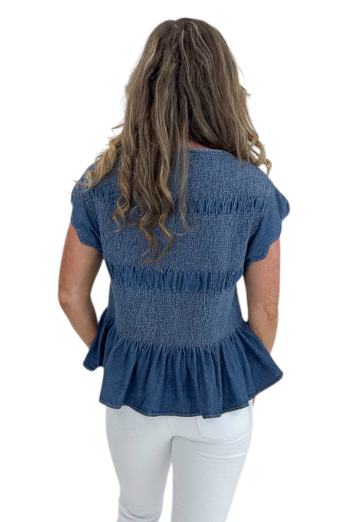 Back view of woman wearing Swagger Boutique’s Denim Smocked &amp; Scalloped Top with jeans against white studio background.