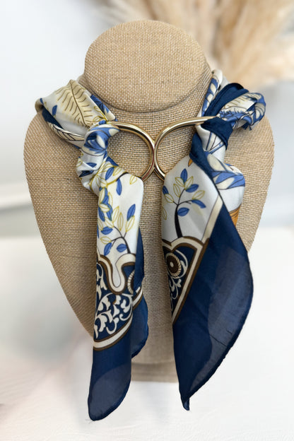 Gold-tone scarf ring enhancer styled on a blue patterned scarf, shown holding the scarf in place on a white studio background
