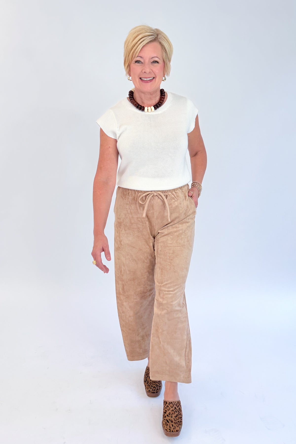 Front view of woman wearing Swagger Boutique’s Light Sand Drift Suede Pants by Z Supply with sweater against white studio background.