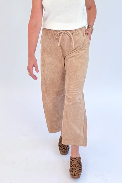 Front view of woman wearing Swagger Boutique’s Light Sand Drift Suede Pants by Z Supply with sweater against white studio background.