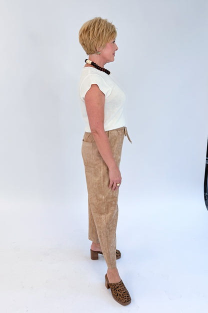 Side view of woman wearing Swagger Boutique’s Light Sand Drift Suede Pants by Z Supply with sweater against white studio background.