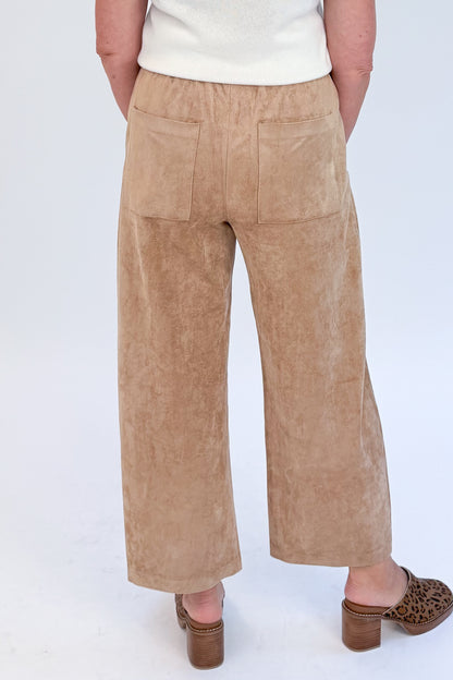 Back view of woman wearing Swagger Boutique’s Light Sand Drift Suede Pants by Z Supply with sweater against white studio background.
