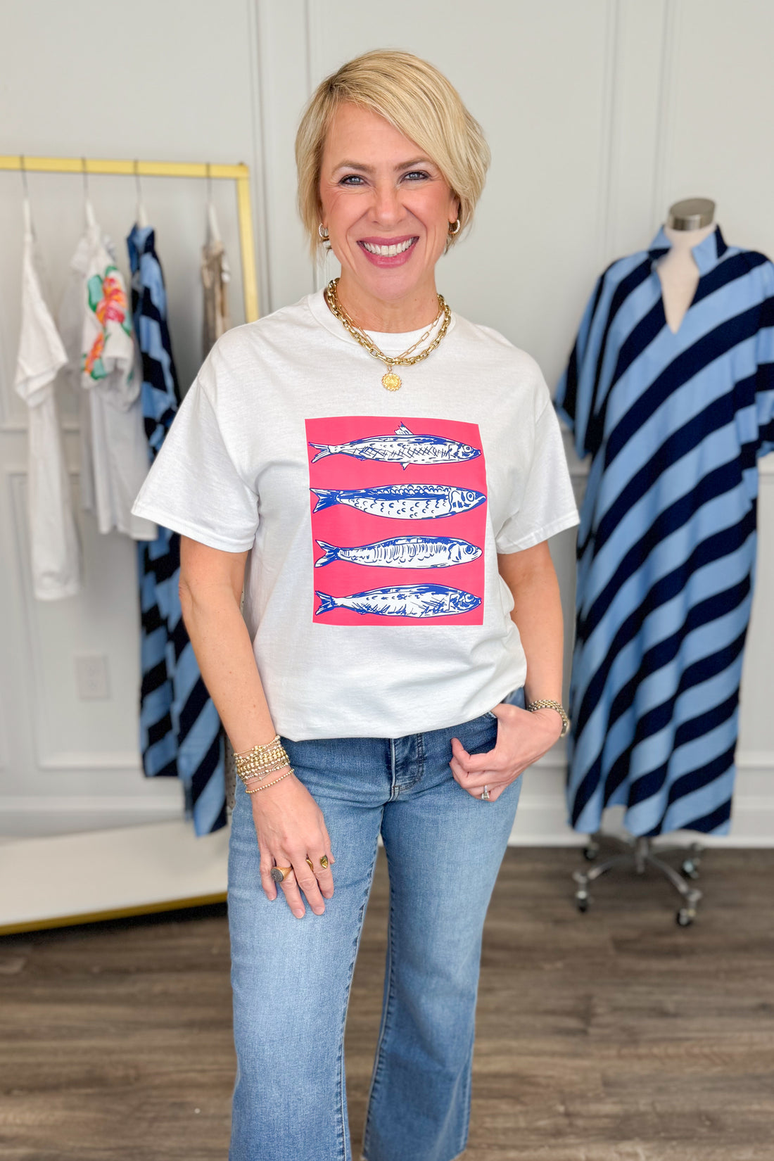 Woman wearing a white t-shirt with a colorful graphic design, standing in a clothing store.