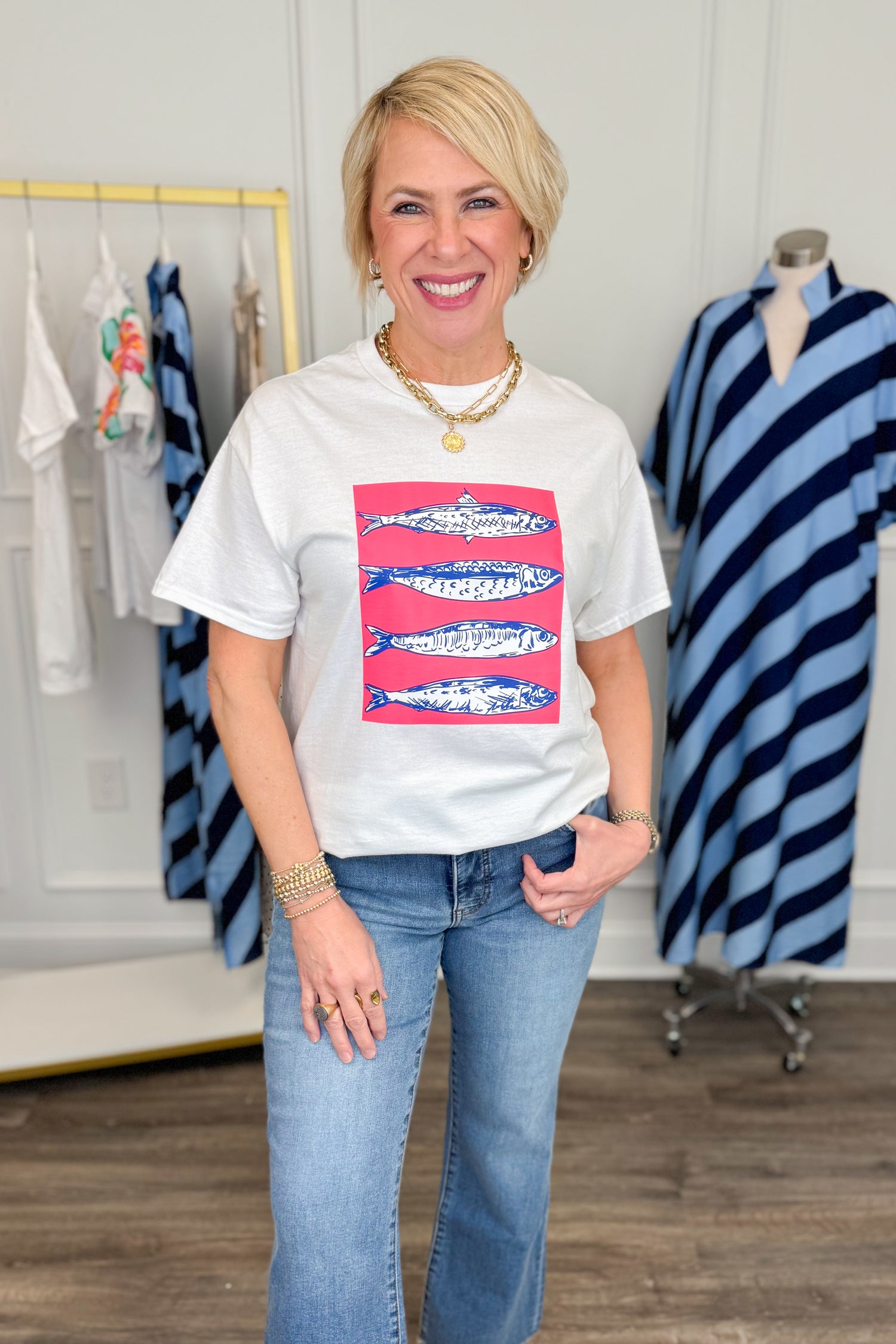 Woman wearing a white t-shirt with a colorful graphic design, standing in a clothing store.