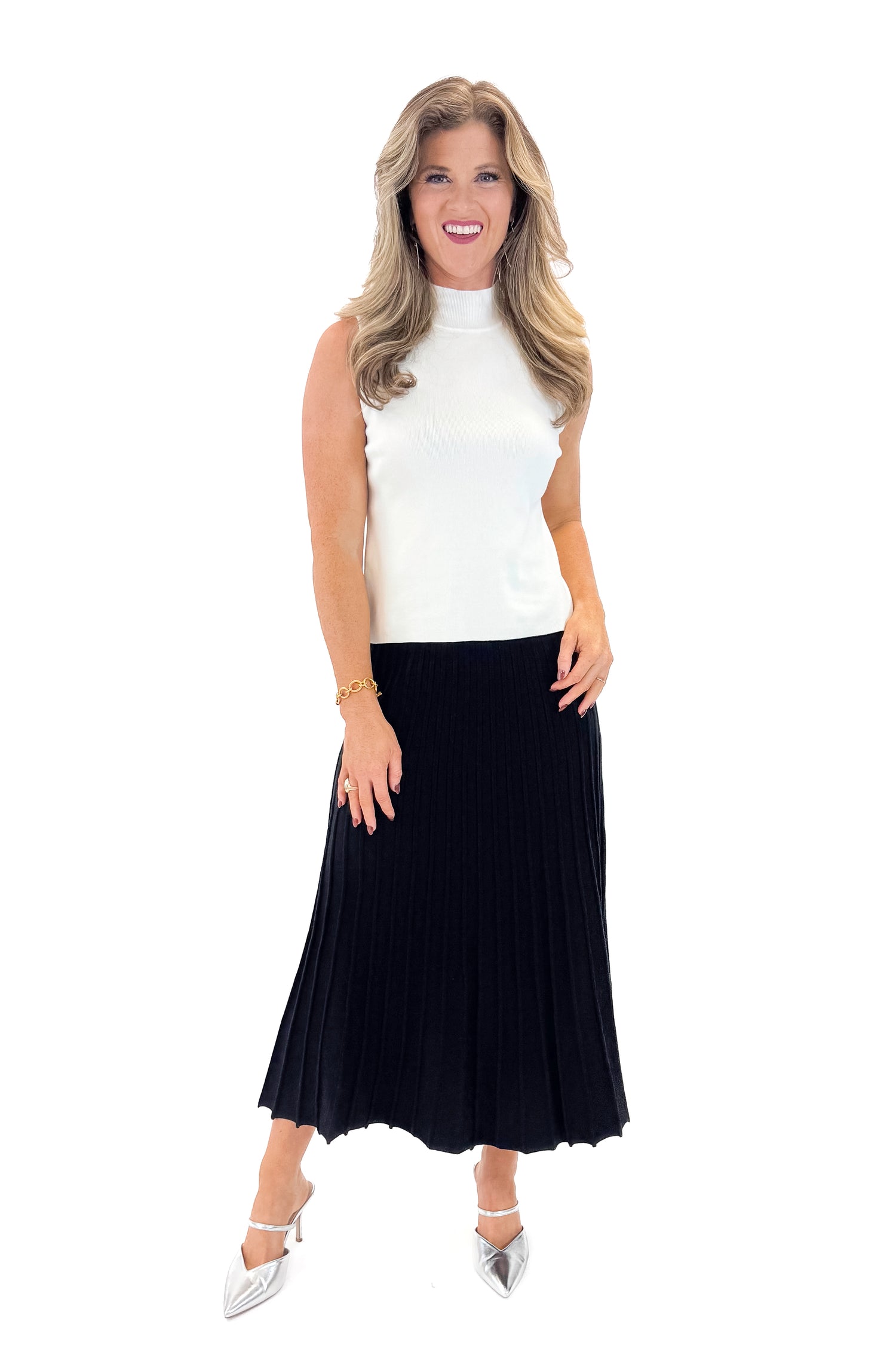 Front view of woman wearing Off White Pearl Detail Mock Neck Top with Black Pleated Sweater Skirt against white studio background.
