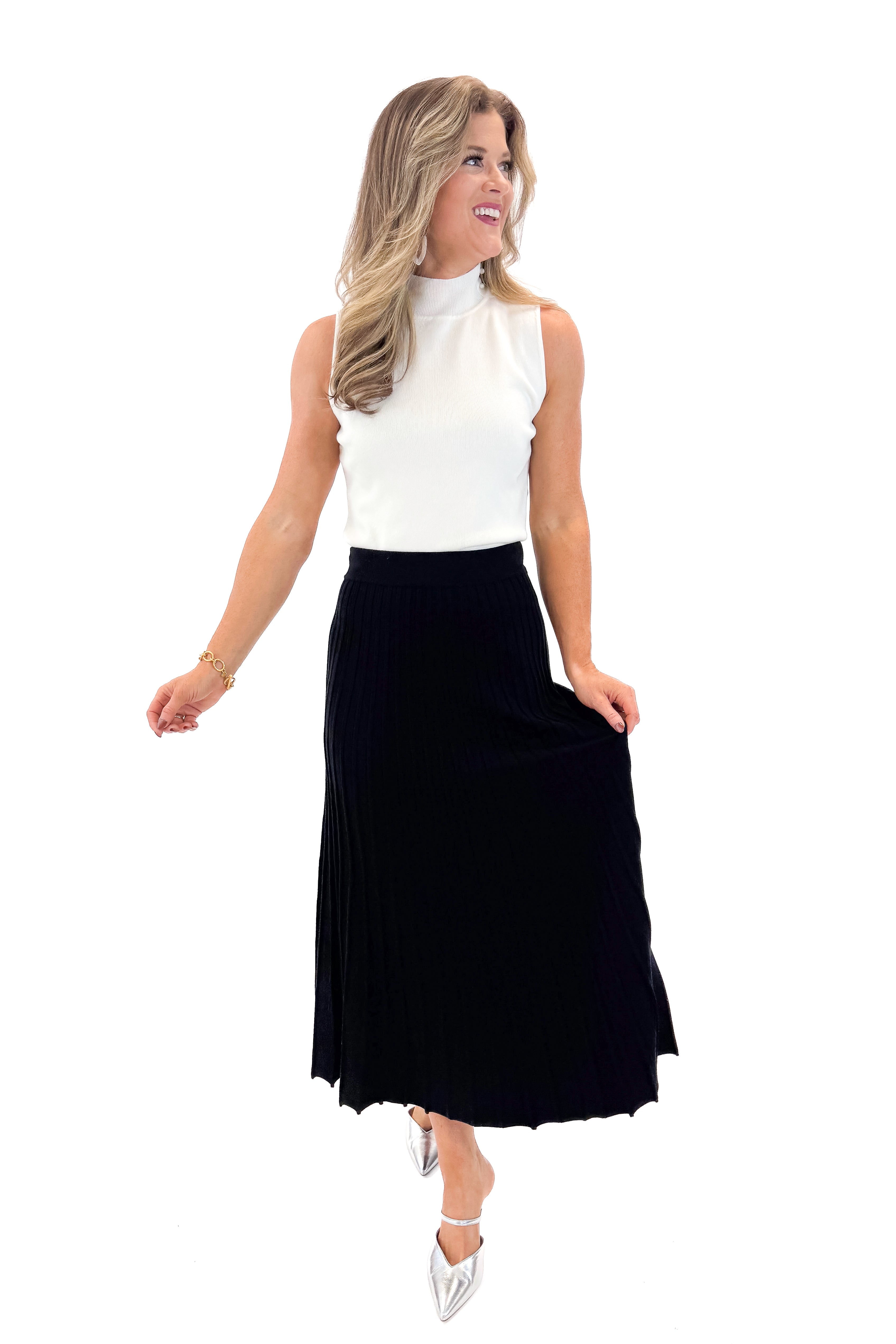 Front view of woman wearing Off White Pearl Detail Mock Neck Top with Black Pleated Sweater Skirt against white studio background.
