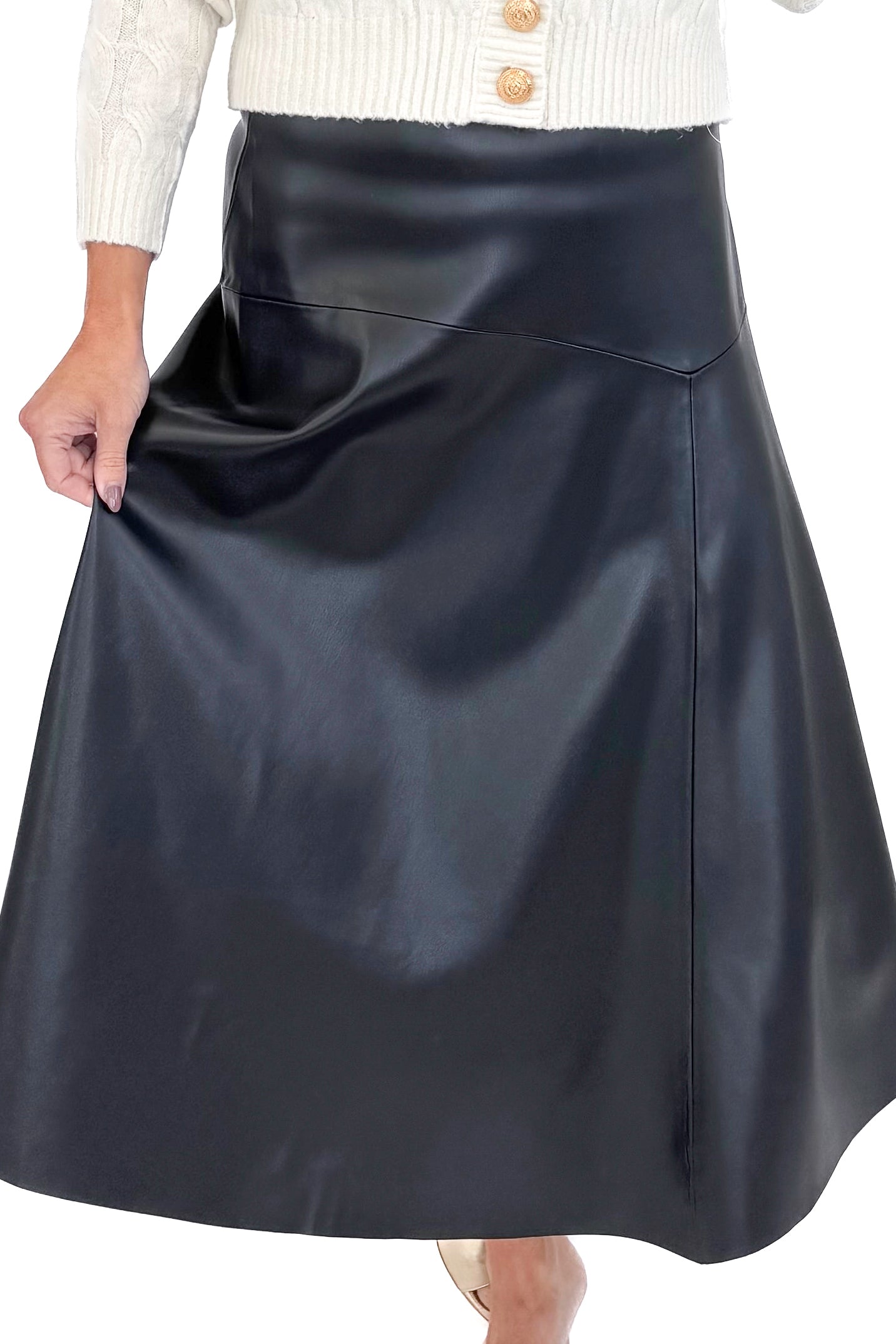 Front close view of woman wearing cream sweater with black faux leather skirt against white studio background.